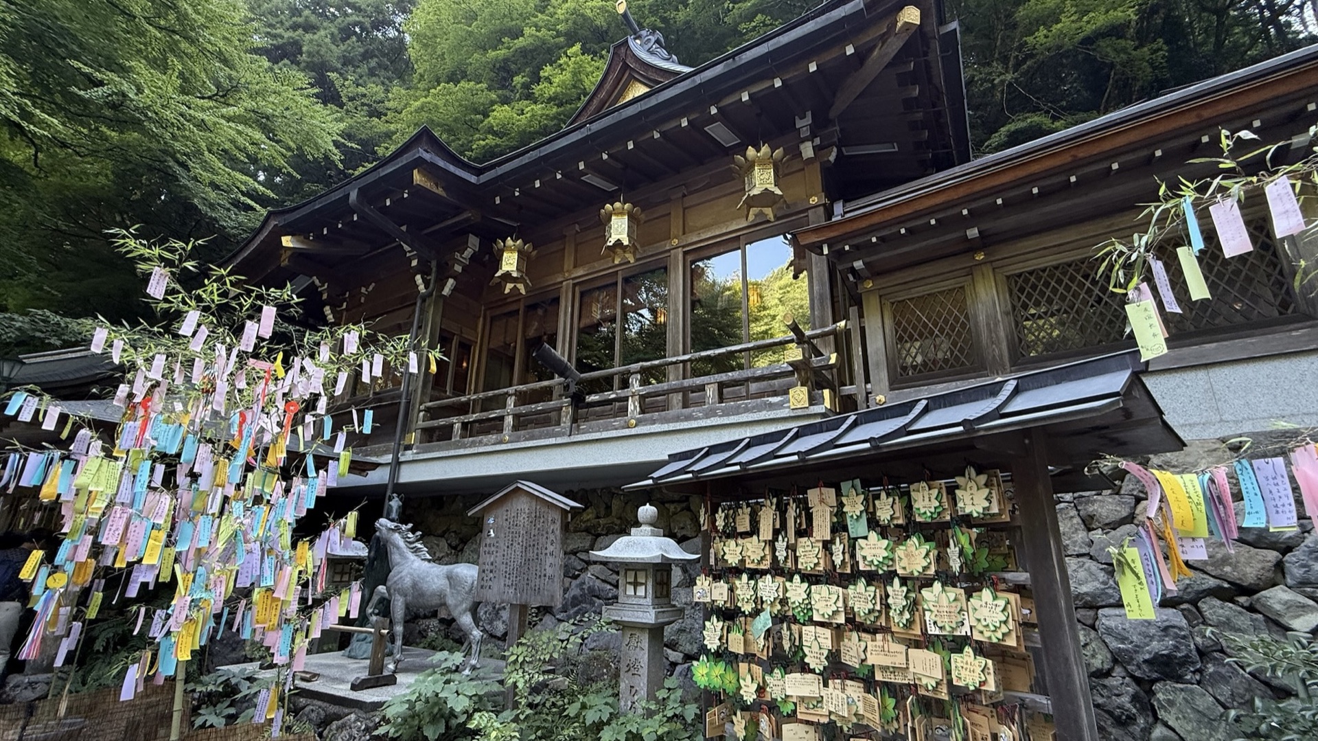 貴船神社本殿，木造社殿前掛滿繪馬與短冊，周圍是茂密山林