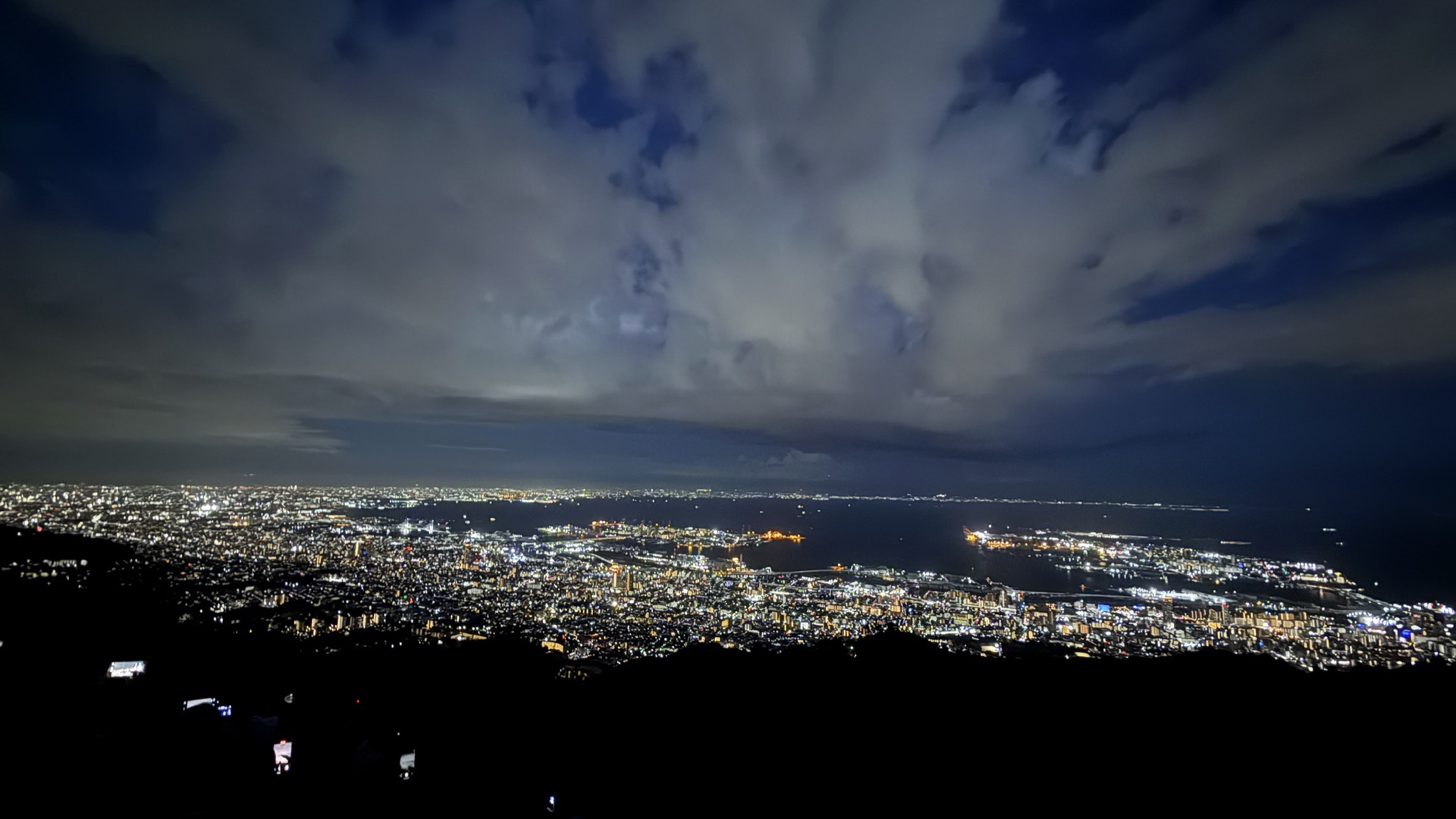 從摩耶山掬星台俯瞰的大阪灣夜景全景,烏雲後方透出城市燈光,視野遼闊