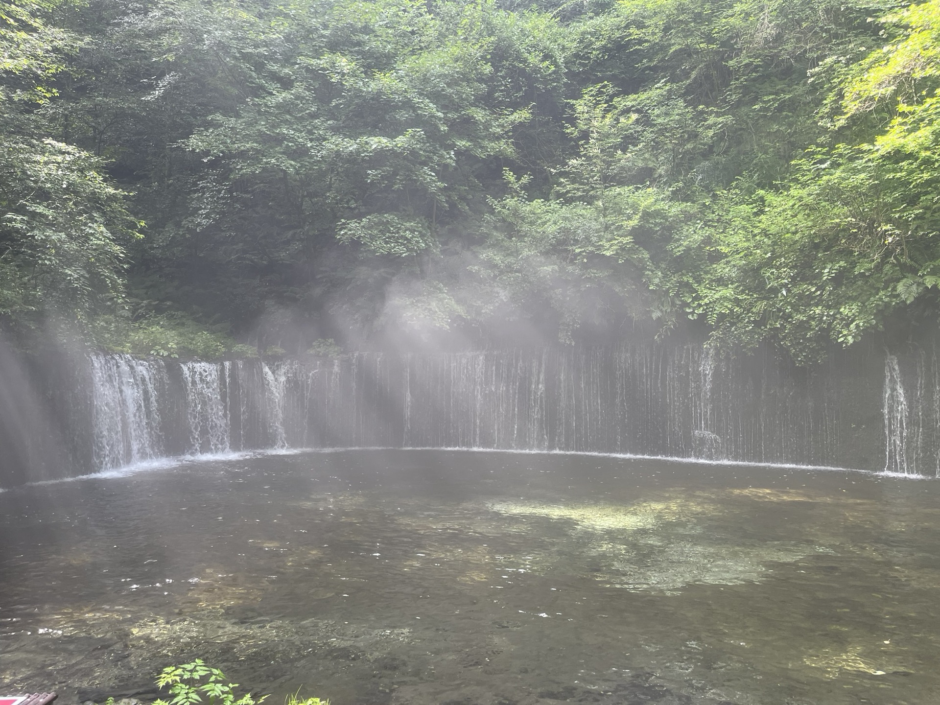 長野縣輕井澤白絲瀑布，半圓弧形岩壁湧出數十條細流形成水幕，濃霧瀰漫整個瀑布空間